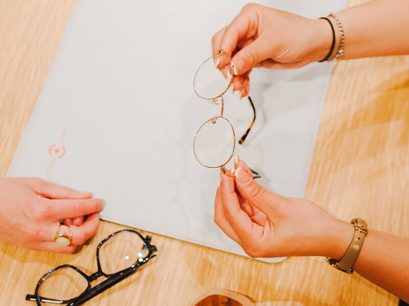 Eine Person hält eine Brille in ihren Händen und präsentiert sie einer anderen Person